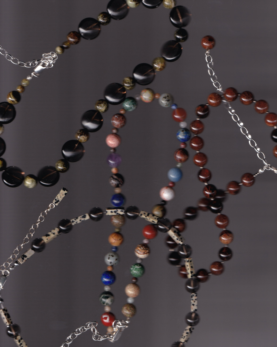 Multiple beaded necklaces with various colored beads on a dark background