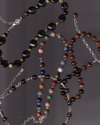 Multiple beaded necklaces with various colored beads on a dark background